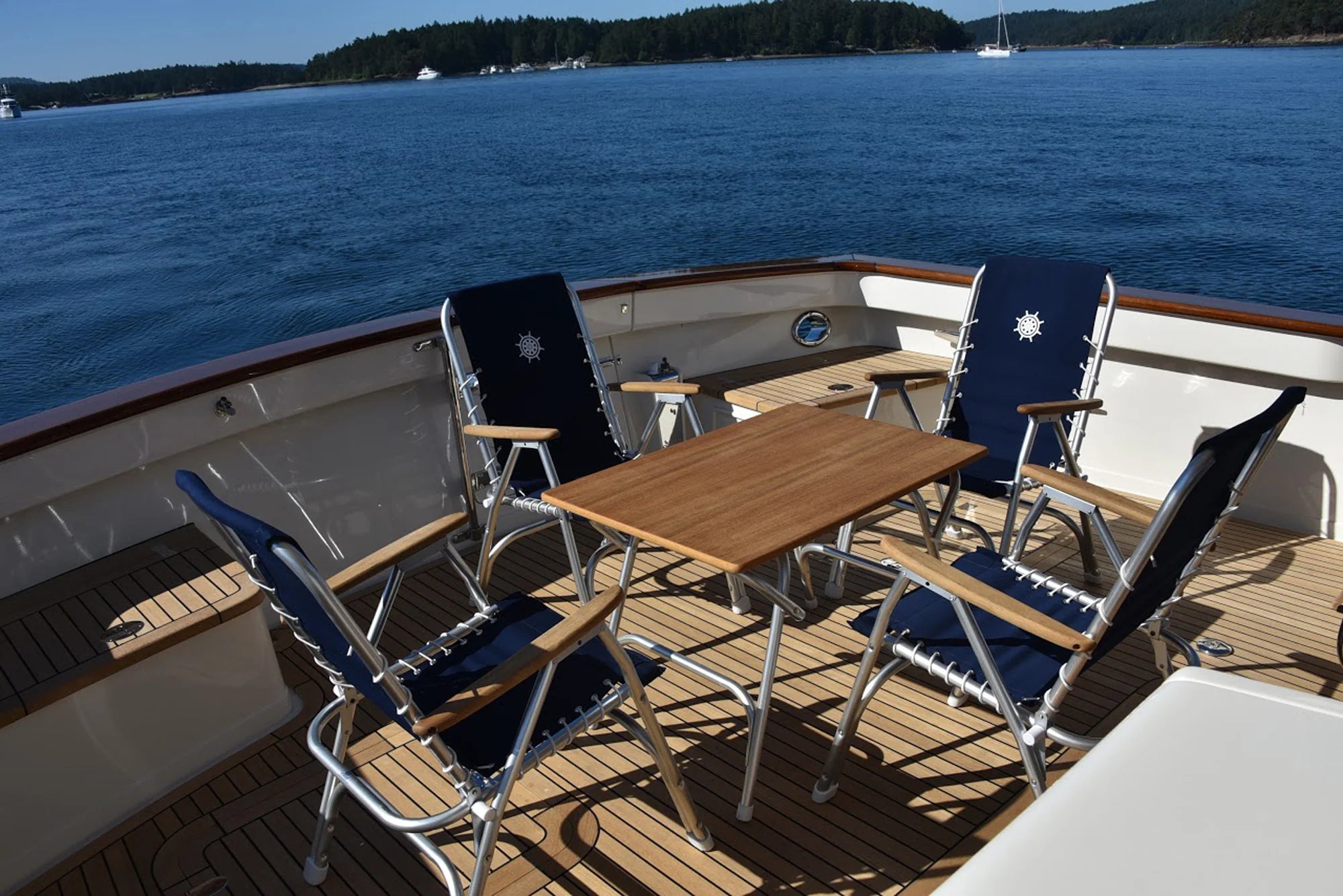 Four Forma Marine Navy Blue M150 Boat Chairs around a M400 teak Boat Table on a beautiful teak boat deck. 