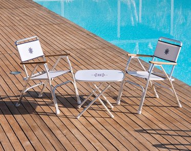 A set of two Forma Marine M100 Boat Chairs along with an M350 Table on a wooden deck by the pool.