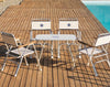 Four Forma Marine M100 White Boat Chairs and a M250 Table set by the pool on a sunny day.